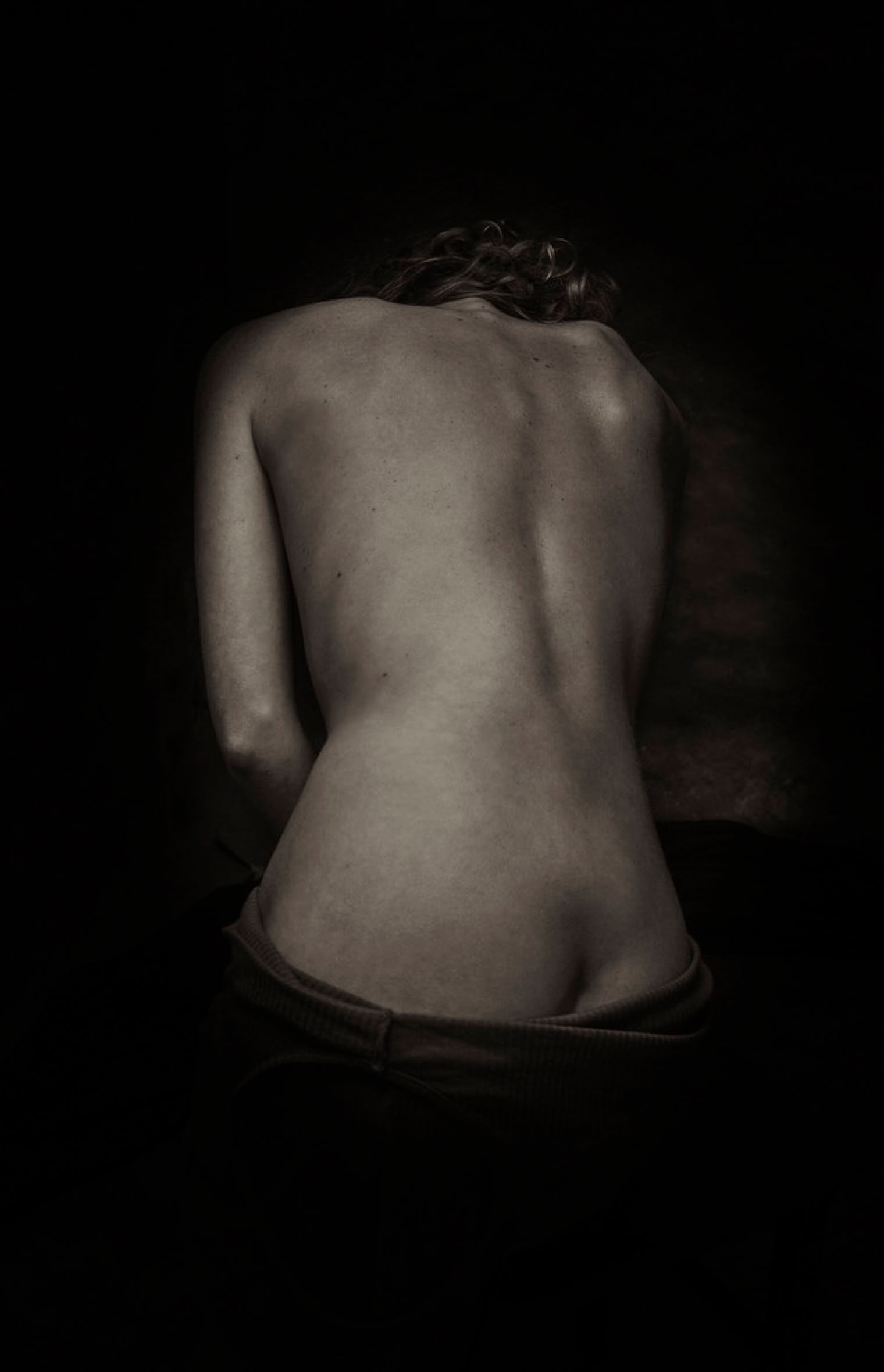 Silent Echo – black and white fine art photography artwork by RAN ART, showing a seated figure from behind with bare back and shoulders, in a quiet and poetic atmosphere.